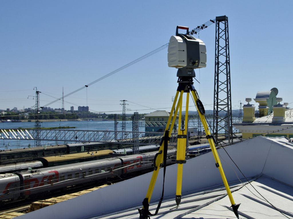 Terrestrischer Laserscanner auf Stativ mit Blick auf Bahngleise und Fluss im Hintergrund
