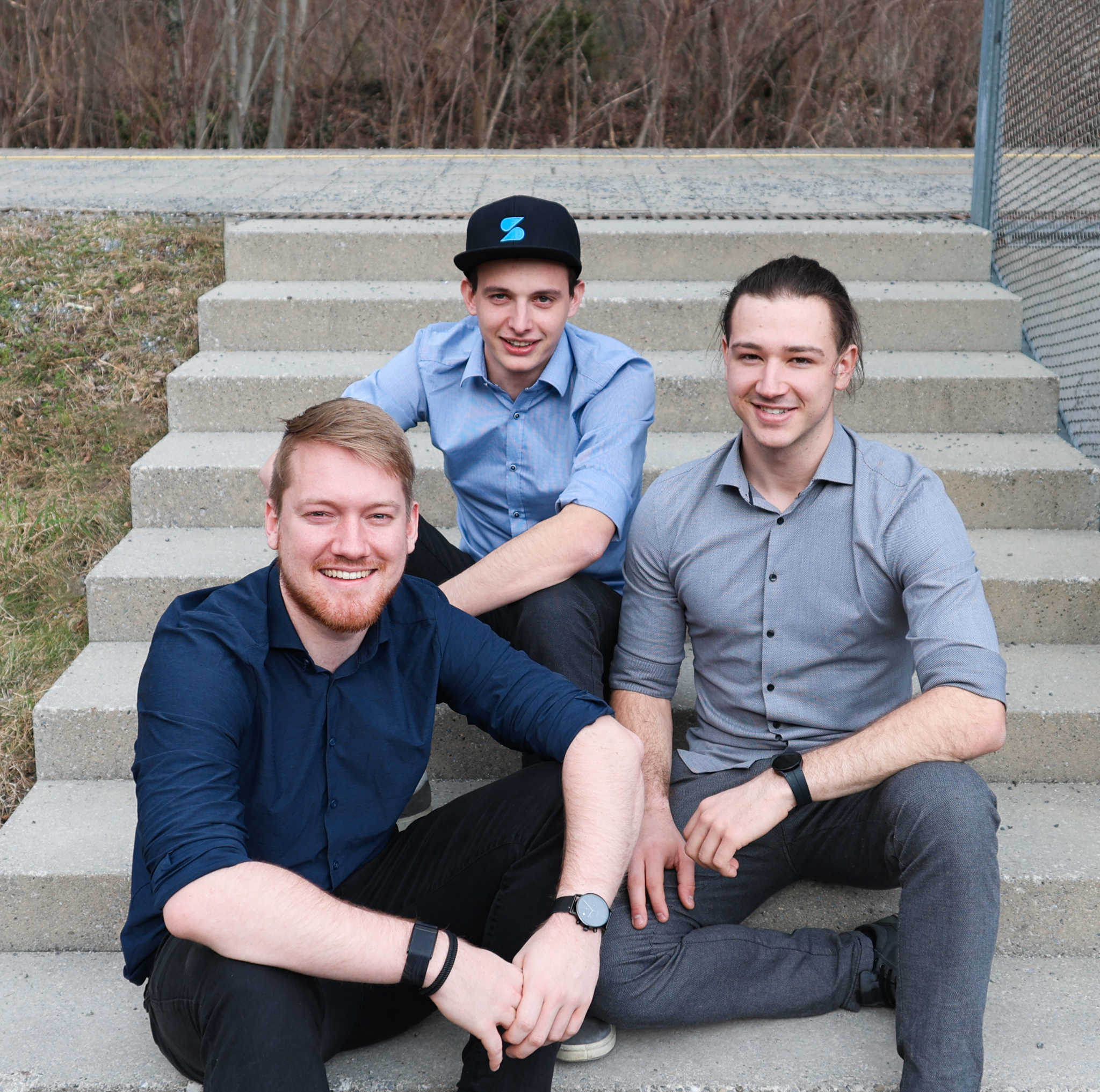 Drei Teammitglieder von Sodex sitzen gemeinsam auf einer Treppe und lächeln in die Kamera